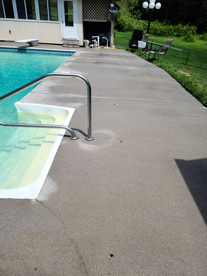 Clean concrete pool deck beside a turquoise swimming pool