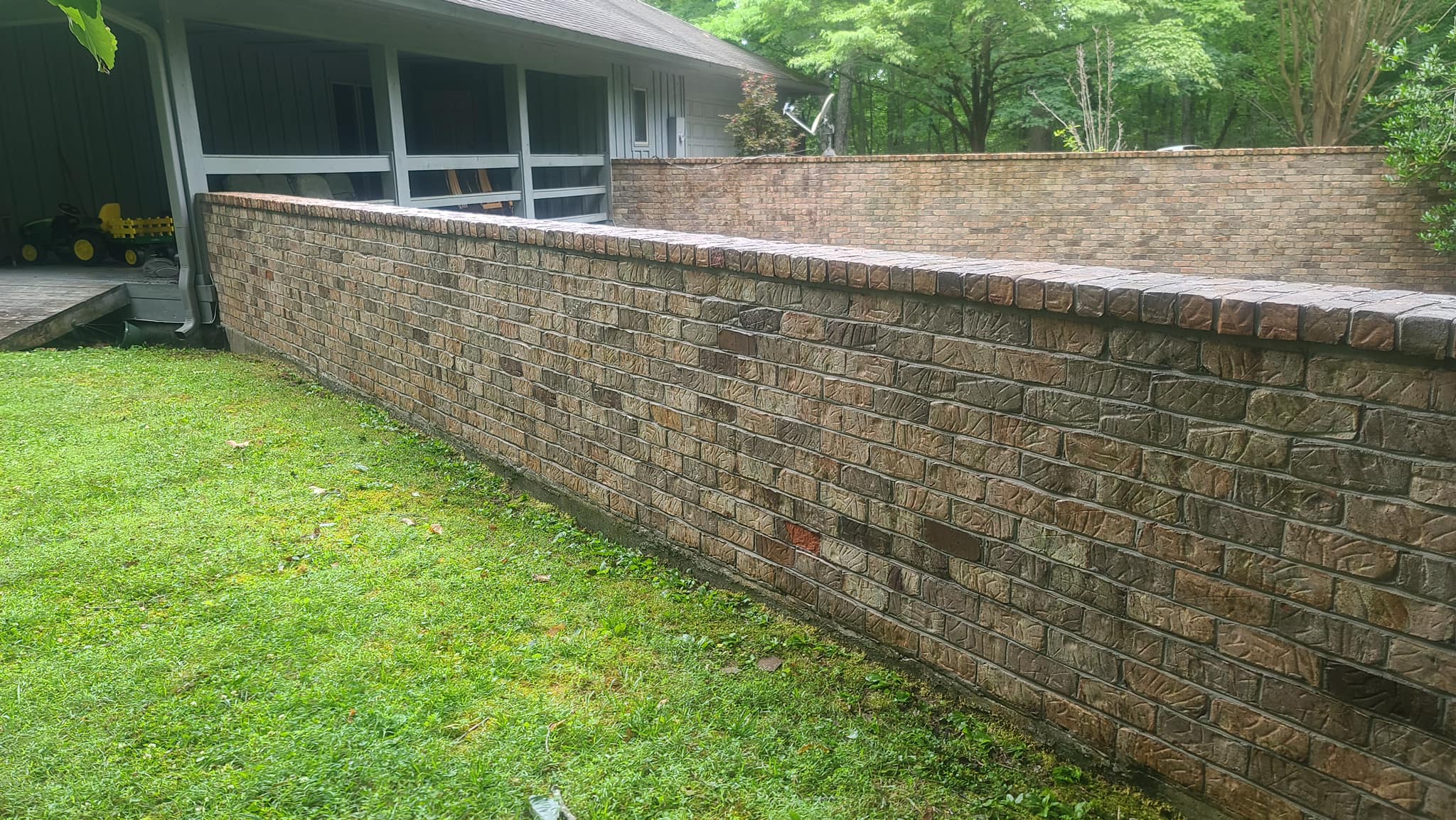 Brick retaining wall with algae and grime staining along the base