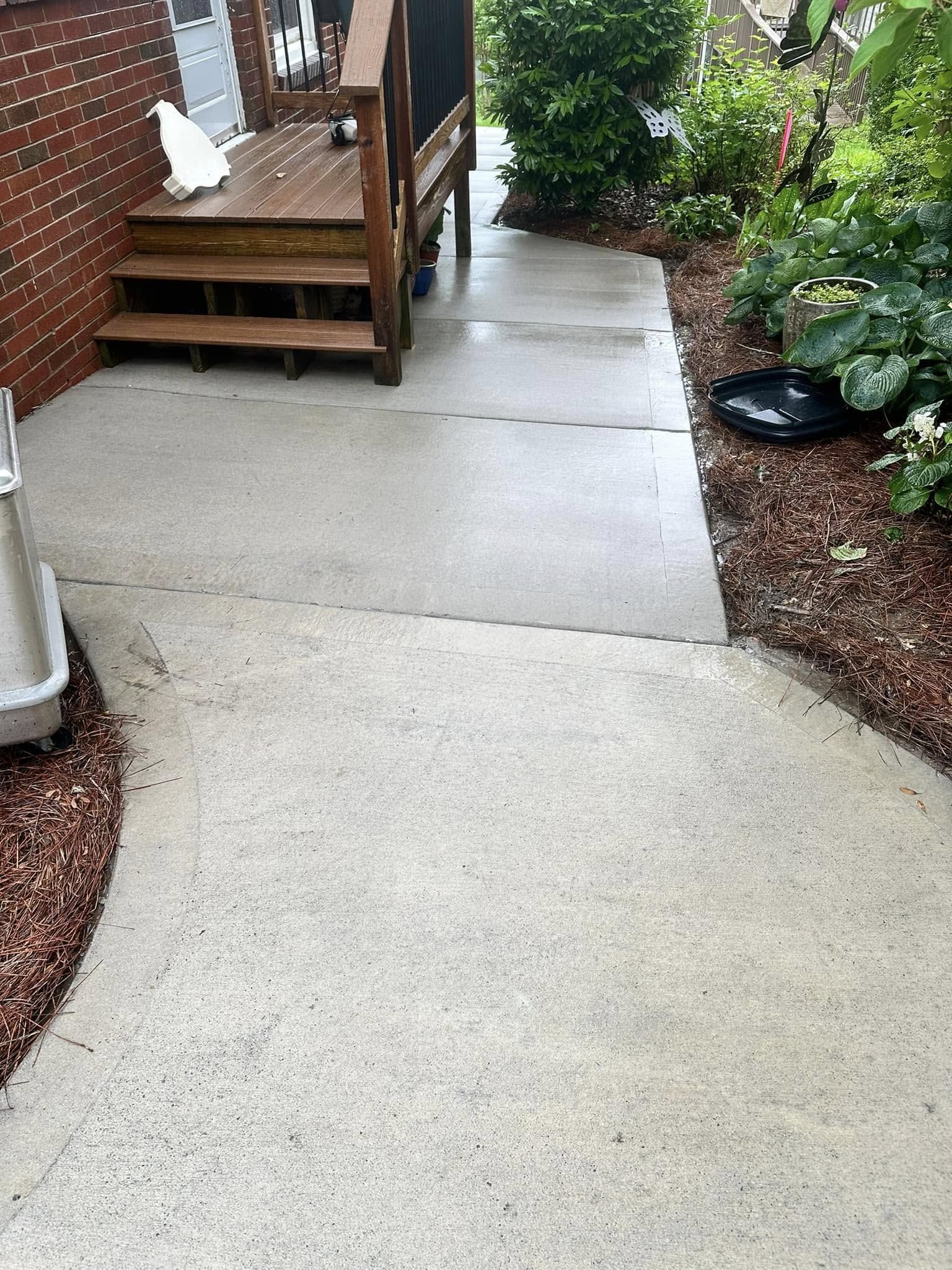 Clean curved concrete walkway leading to a red brick home