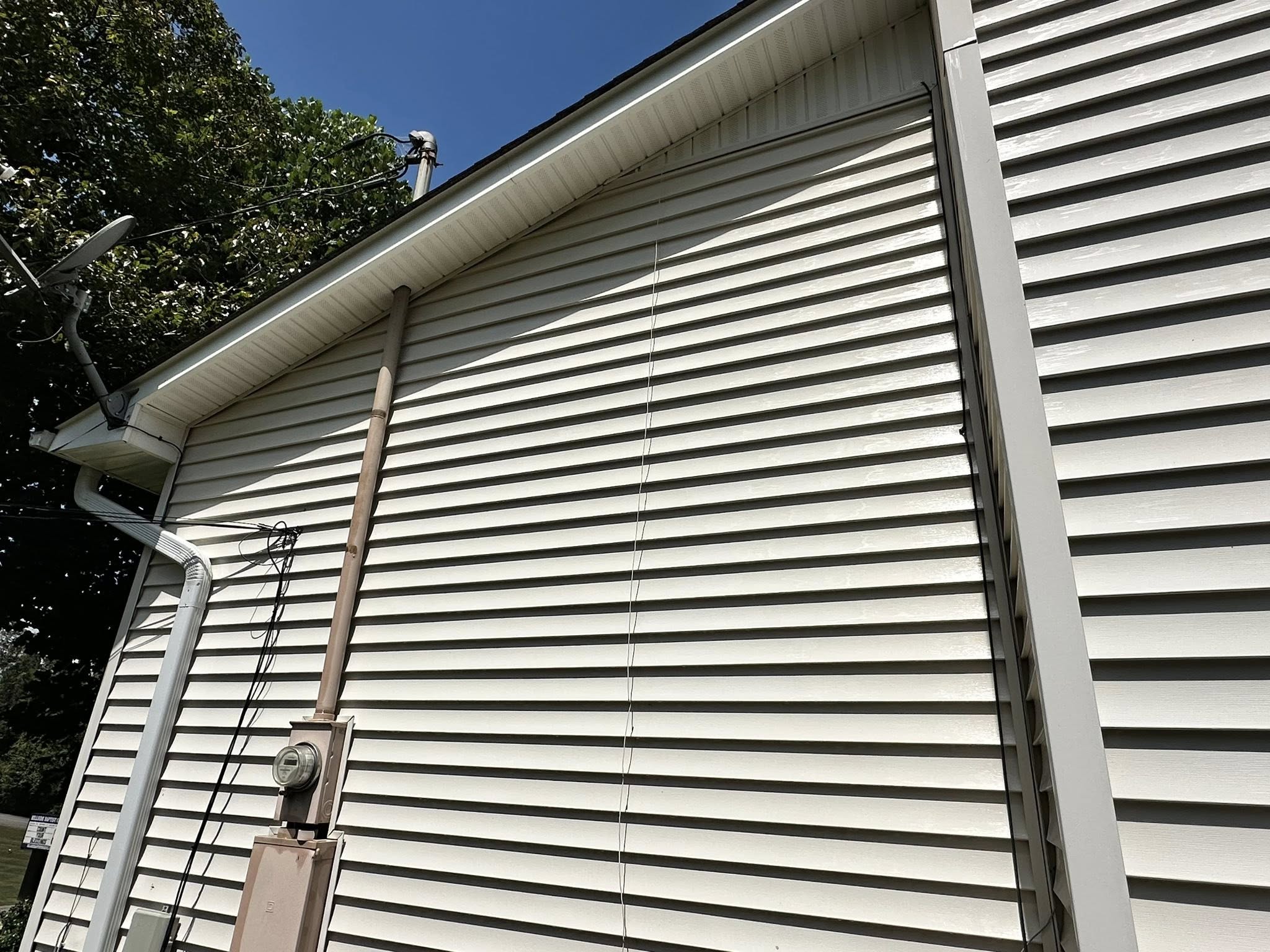 Clean white vinyl siding against a bright blue sky after soft washing